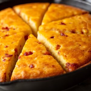 fatback cornbread, cornbread, fatback pork, cast iron skillet, golden brown, sliced bread, red pepper flecks, baked cornbread, southern cooking, homemade bread, comfort food, traditional recipe, rustic cuisine, authentic cooking, savory bread, food photography, recipe content, cooking blog, breakfast bread, side dish, culinary styling, home cooking, warm tones, appetizing, ai generated