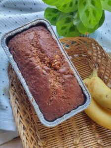 Freshly baked banana walnut bread with bananas on a wicker tray.